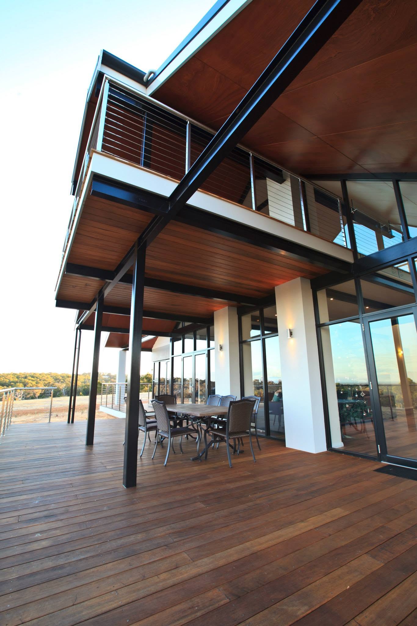 Covered timber deck on a custom new build, with exposed steel columns and a first-floor balcony above