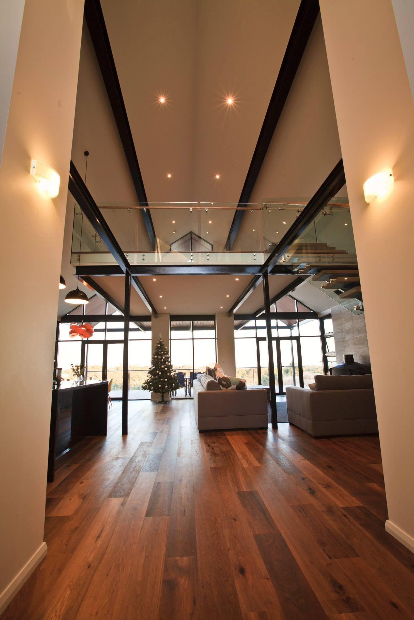 Double-height entry hall framed by black steel portal beams, looking through to the living area