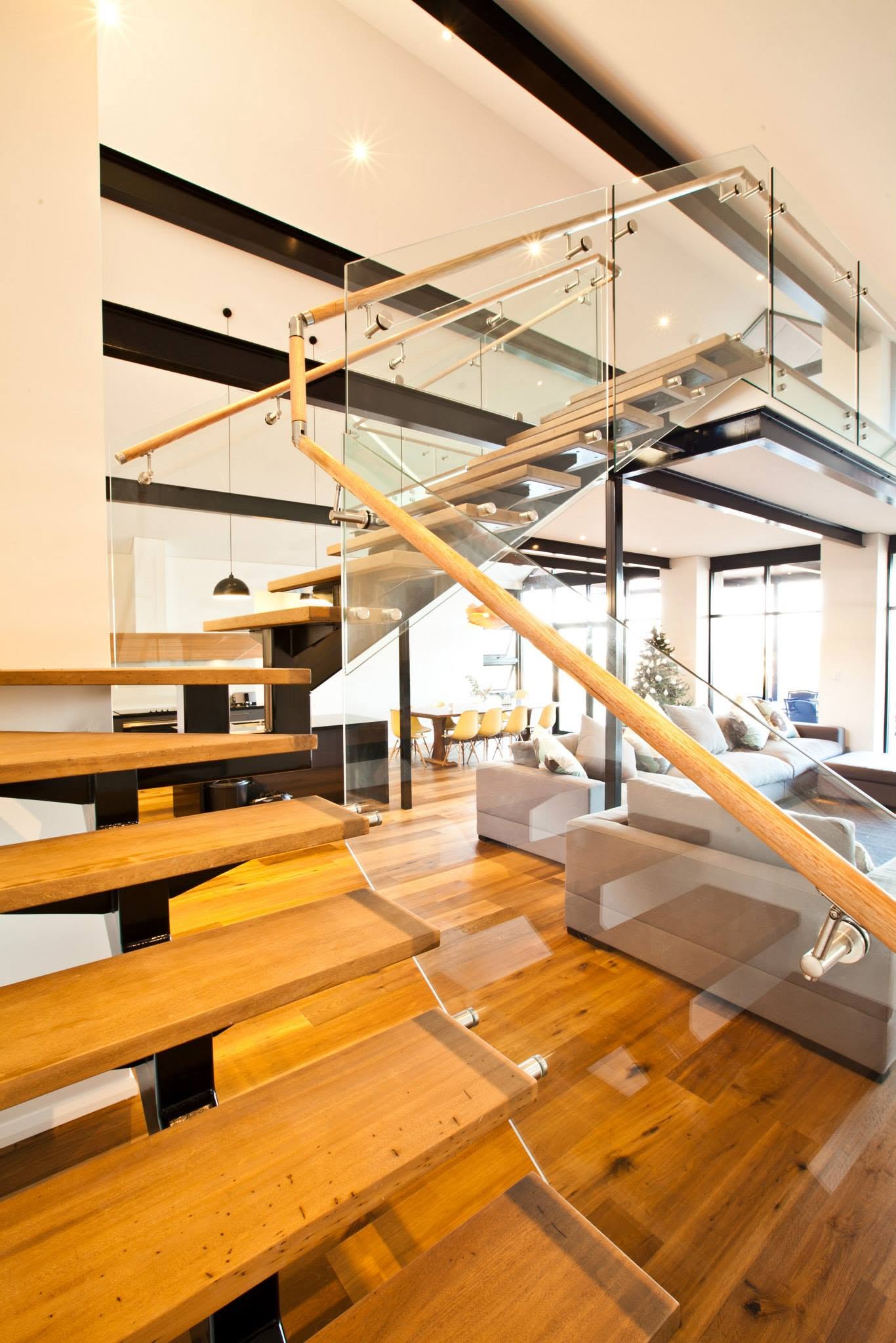Floating timber treads with a glass balustrade and oak handrail rising to a mezzanine level