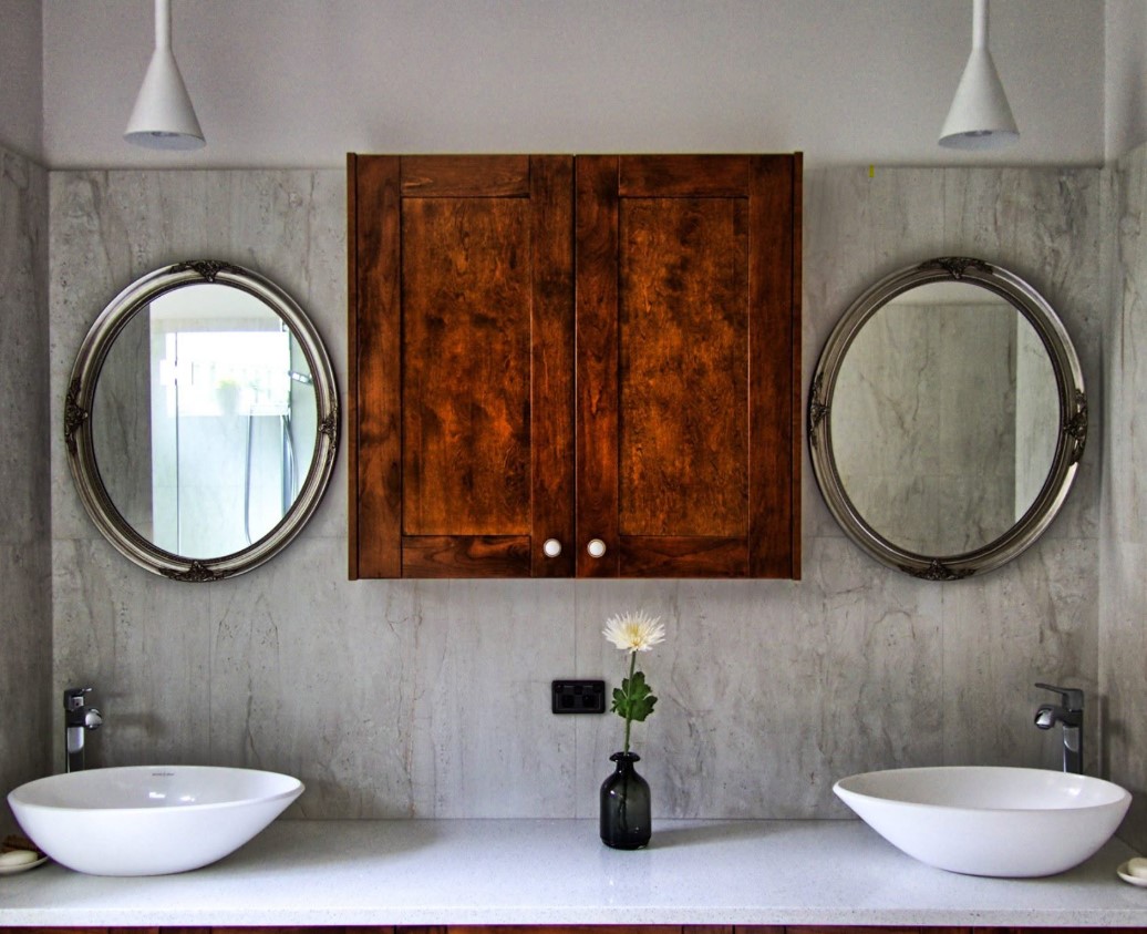 Bathroom with twin vessel basins, oval framed mirrors and full-height marble-look wall panels