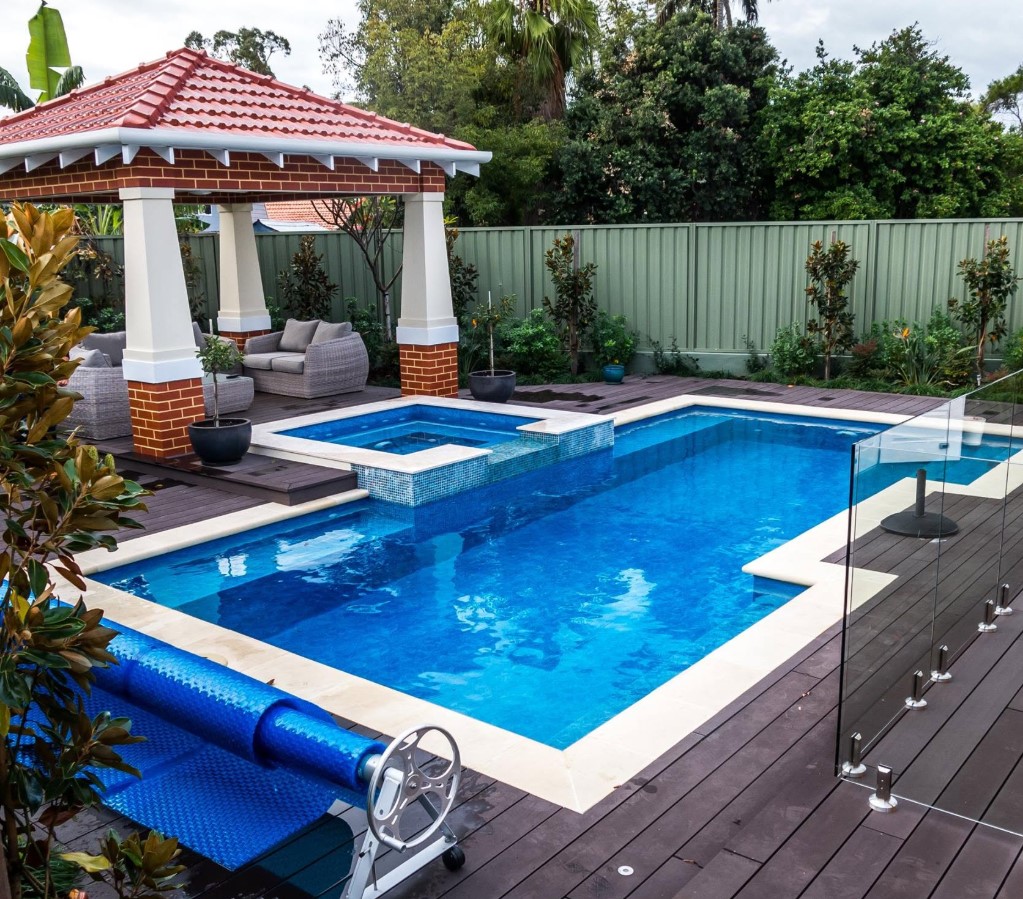 Swimming pool and spa with a brick and terracotta-roofed cabana alongside a timber deck