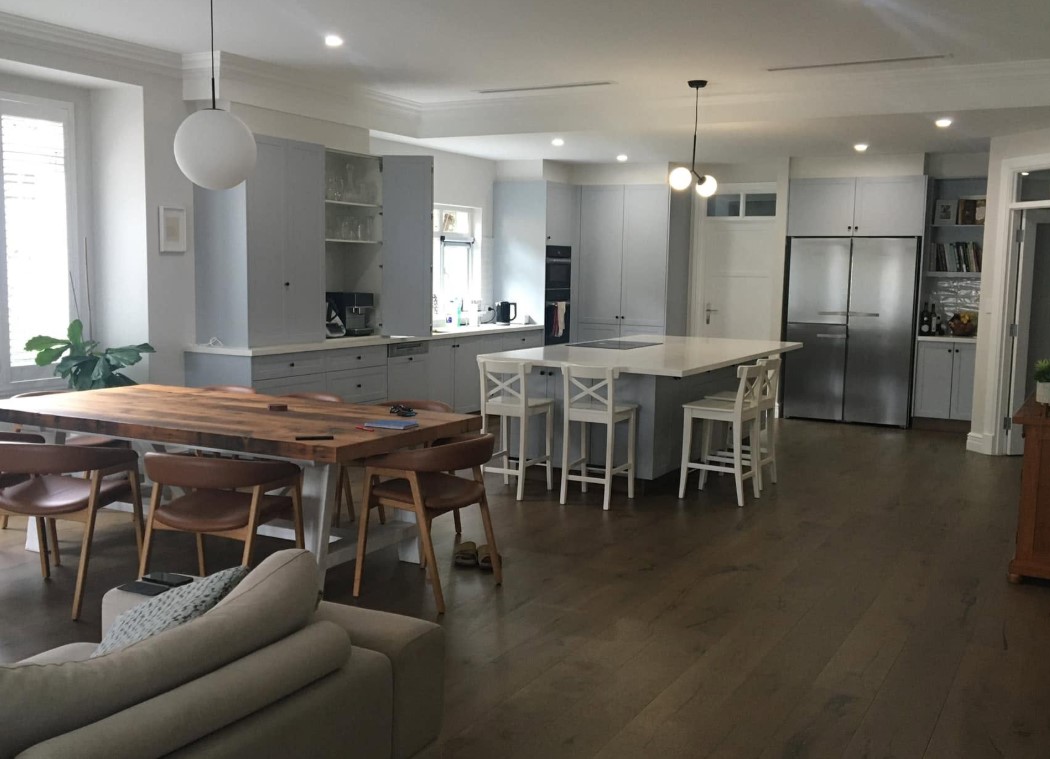 Renovated shaker kitchen with a stone island bench opening onto a dining and living space