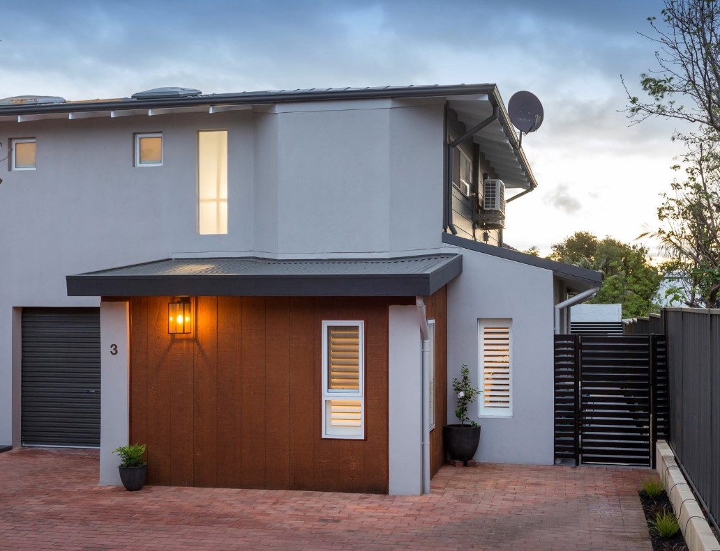 Contemporary grouped dwelling at dusk with timber cladding, rendered walls and a skillion roof